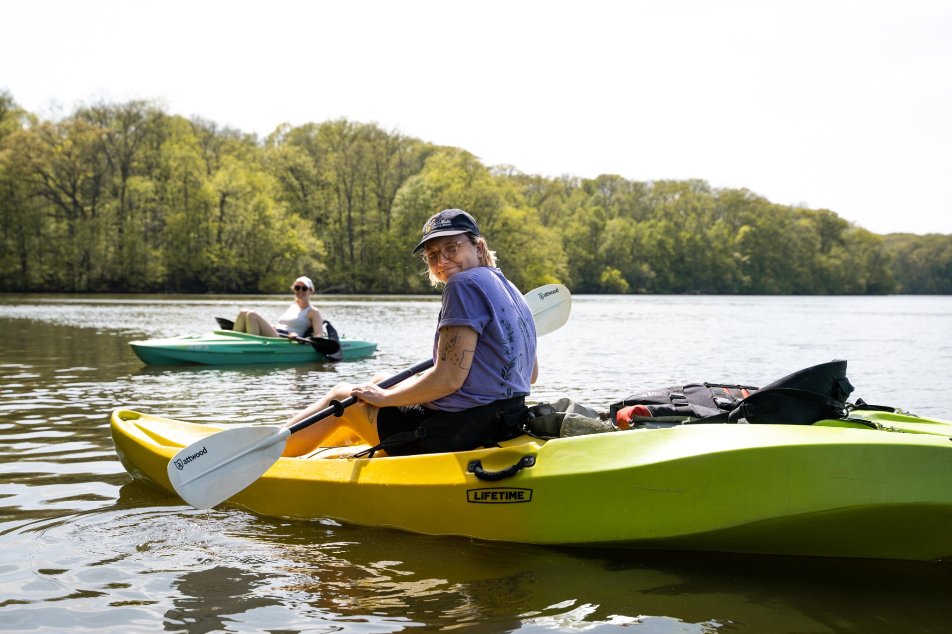Two paddlers kayaking on a calm tree-lined lake