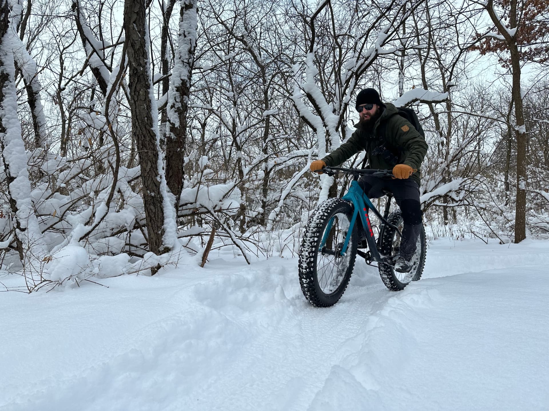A rider on a fat-tire bike carving a packed snow trail through a winter forest